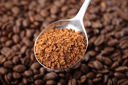 A jar of instant coffee granules dissolving in hot water